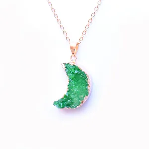 Macro detail of crescent moon pendant featuring green crystal druzy and rose gold plating
