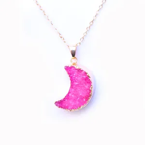 Close-up of pink crescent moon crystal pendant with gold-plated edges and slim metal chain