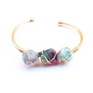 Detail van met koperdraad omwikkelde natuurlijke kristallen op een gouden verstelbare armband