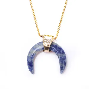 Detail of blue natural stone crescent pendant with gold clasp and sparkling rhinestones