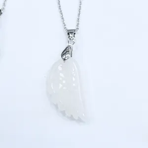 Détail du pendentif aile d'ange en agate blanche avec gravures de plumes et chaîne argentée