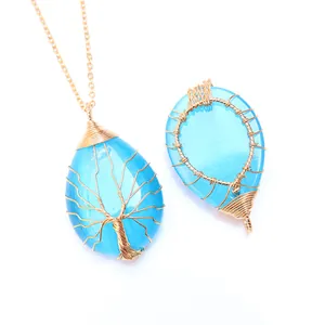 Détail macro d'un pendentif goutte bleu avec arbre de vie artisanal en fil doré tressé