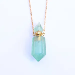 Close-up van groene kristallen parfumfles hanger met gouden dop en fijne ketting