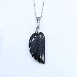 Détail macro du pendentif aile d'ange en agate noire sculptée sur une chaîne argentée