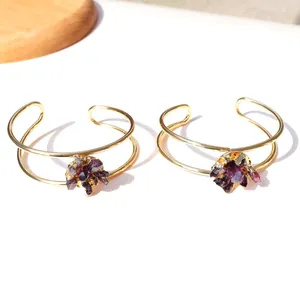 Detail van gouden dubbele armbanden met natuurlijke paarse amethist kristallen