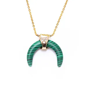 Detailed close-up of malachite horn pendant with gold hardware and inlaid crystals