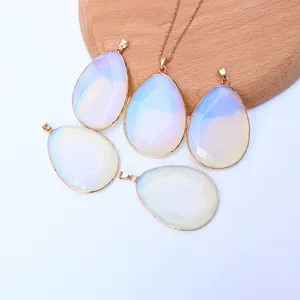 Detail of five teardrop opal pendants with gold plating on a wooden display stand