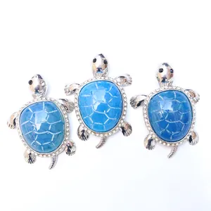 Detailed view of silver turtle pendants with blue shell pattern and crystal stones