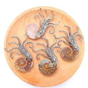 Octopus ammonite fossil pendant in silver metal on wooden tray with white background