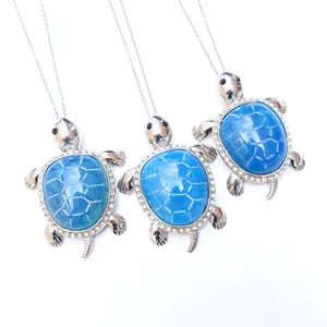 Three blue agate turtle necklaces with silver plating and rhinestones on white backdrop