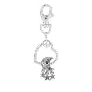 Détail d'un cadre cœur argenté avec breloques lune en zircon bleu et étoiles sur mousqueton