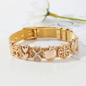 Bracelet en maille dorée style montre avec breloques trèfle et cœur sur fond blanc