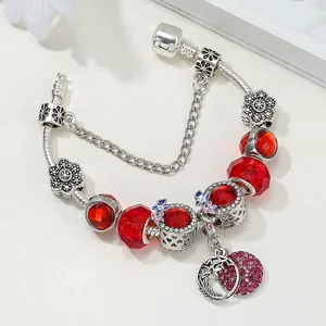 Détail du bracelet chaîne serpent avec perles en cristal rouge et breloques arbre de vie