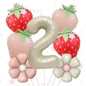 Close-up of strawberry and daisy foil balloons with a cream number 2 for birthday party