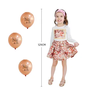 Detail of rose gold Bride to Be balloons and floral print girl outfit for bridal party