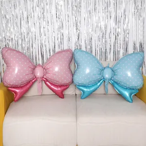 Detailed view of pink and blue bow foil balloons with white dots on a cozy sofa