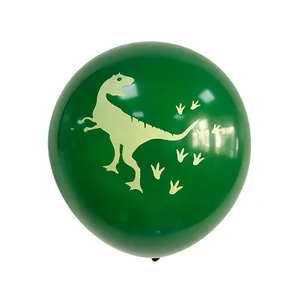 Gros plan d'un ballon de fête vert foncé avec des silhouettes de dinosaures et empreintes