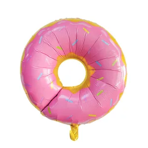 Macro detail of donut shaped foil balloon with pink frosting and colorful sprinkles decoration