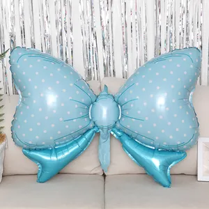 Blue bow foil balloon with white polka dots placed on a sofa for party decoration