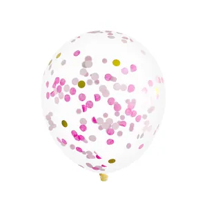 Macro shot of clear party balloon with pink and gold confetti dots for unicorn birthday