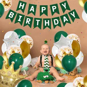Dettaglio del set primo compleanno con striscione verde e palloncini colorati