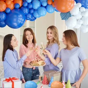 Scena di festa con arco di palloncini blu e arancioni e ventagli di carta eleganti