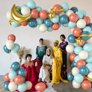 Gender reveal balloon arch with pink and blue stars and women in elegant ethnic dresses