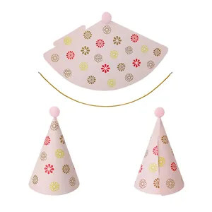 Detail of pink birthday party cone hats with daisy patterns and pom-poms