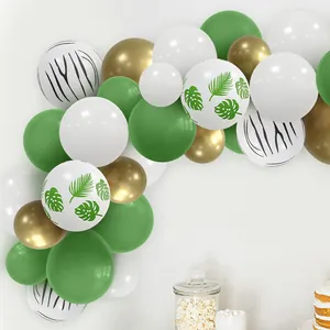 Detail of jungle theme balloon arch with monstera leaves and metallic gold balloons