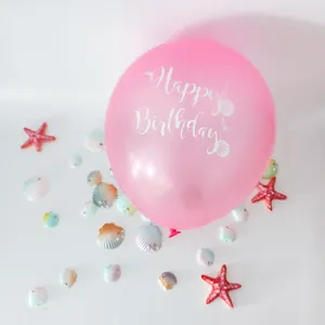 Detail of pink mermaid latex balloon with white Happy Birthday print and sea shells