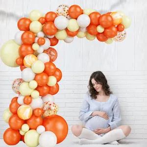 L-shaped orange and beige balloon arch decor with gold confetti for baby shower party