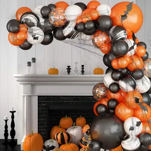 Halloween balloon arch kit with bat decals spider web and pumpkins by a white fireplace
