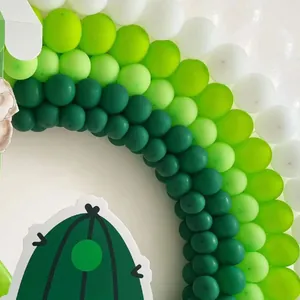 Detailed close-up of green gradient balloon arch with cactus decoration for party events