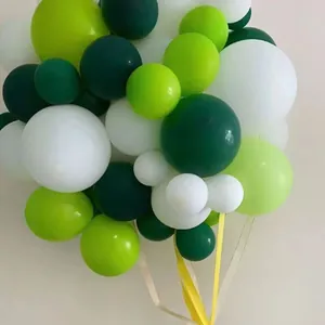 Close-up of mixed green and white matte latex balloons with elegant hanging ribbons