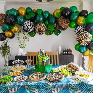 Jungle safari theme party balloon arch with animal prints, gold accents and palm leaves