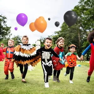 Kids in Halloween costumes with purple, orange and black balloon arch in the park