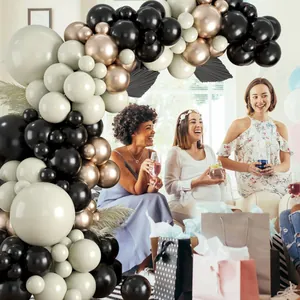 Dettaglio di un arco di palloncini nero, bianco crema e oro rosa con foglie decorative