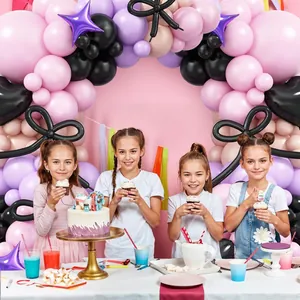 Detail of pink and purple balloon arch kit with black bows for party decorations