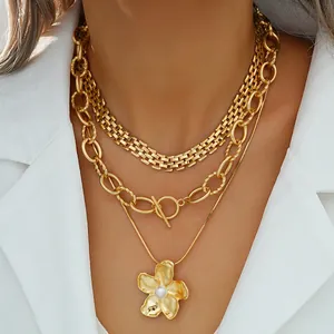 Conjunto de collar dorado de tres capas con colgante de flor de perla sobre traje blanco