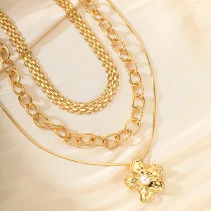 Detalle de conjunto de collares dorados con colgante de flor y perla y cadenas mixtas