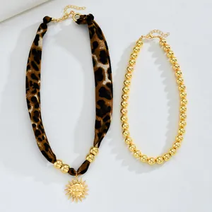 Détail du collier en tissu léopard et pendentif soleil doré avec fermoir mousqueton