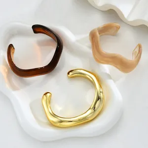Detail of irregular wave resin and gold bracelets on a ceramic display tray