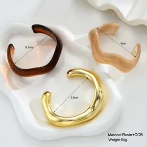 Three irregular wavy open resin bracelets in amber, marble beige, and gold finish