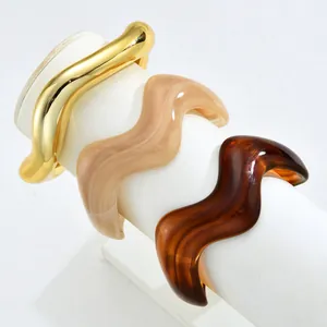Close-up of resin and gold wavy bangles in amber, cream, and metallic finishes