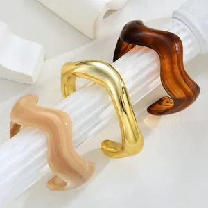 Detailed close-up of wavy resin bangles in gold, tortoiseshell and marble patterns