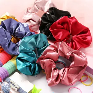 Détail de chouchous en satin de soie colorés et d'élastiques sur fond rose