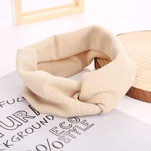Detailed texture of beige ribbed knit headband on a rustic wooden background