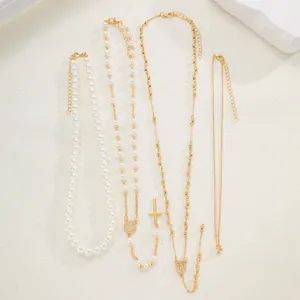 Nahaufnahme eines 4-teiligen goldenen Schicht-Halsketten-Sets mit Perlen und Kreuzanhänger