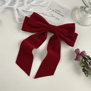Detail of a large red velvet bow hair clip with vintage texture on a white background