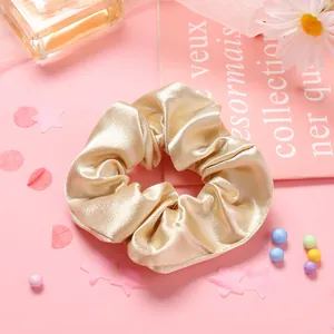 Gros plan sur un chouchou en satin doré champagne avec texture soyeuse et fleurs
